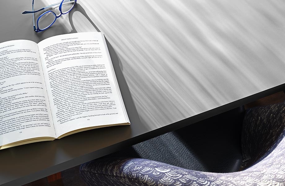Table grise avec un livre ouvert, des lunettes et une chaise